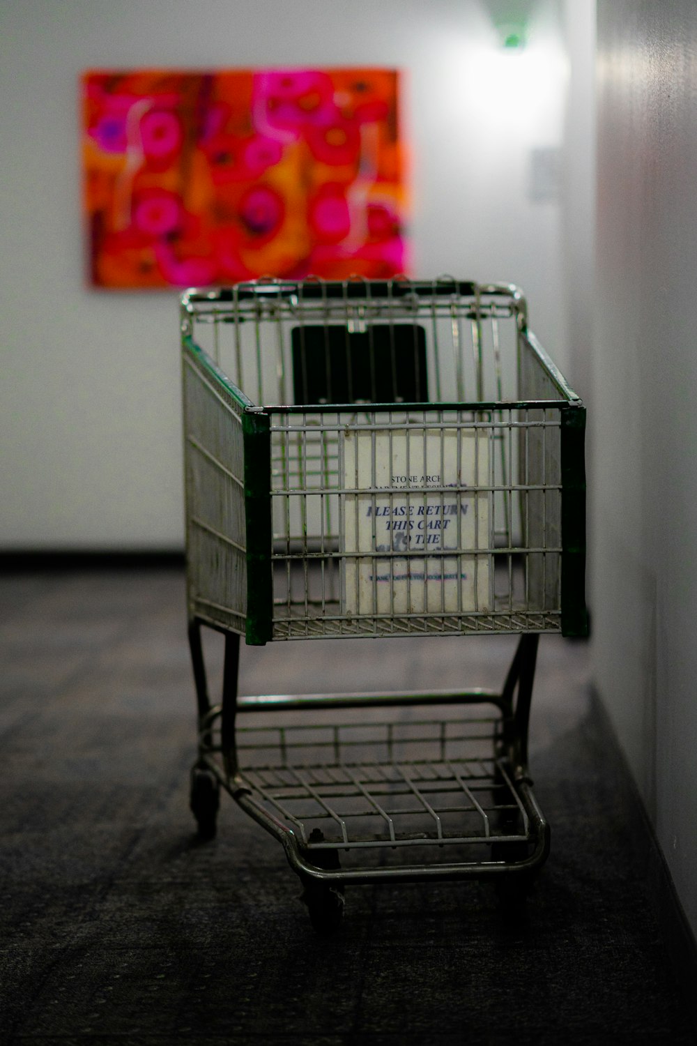 Carrello della spesa grigio vicino al muro bianco