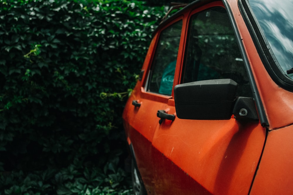 orange car parked near green trees during daytime