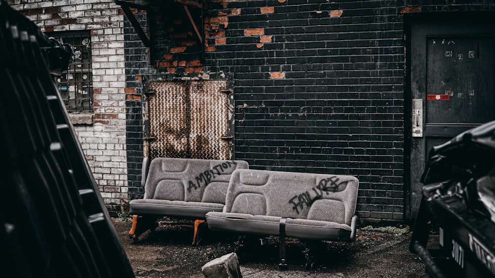 black and white bench beside brick wall