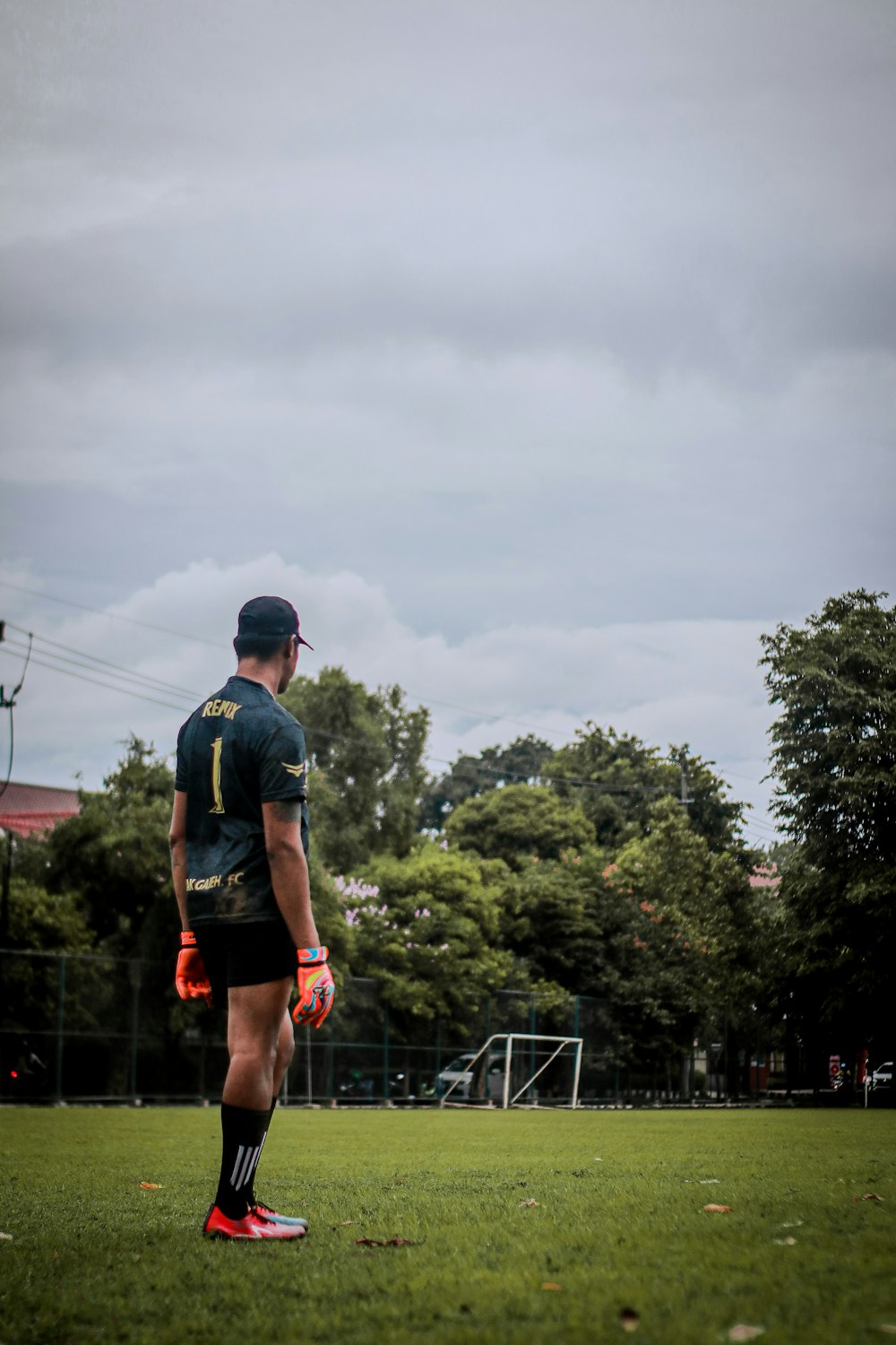 man in black t-shirt and black shorts standing on gray metal fence during daytime