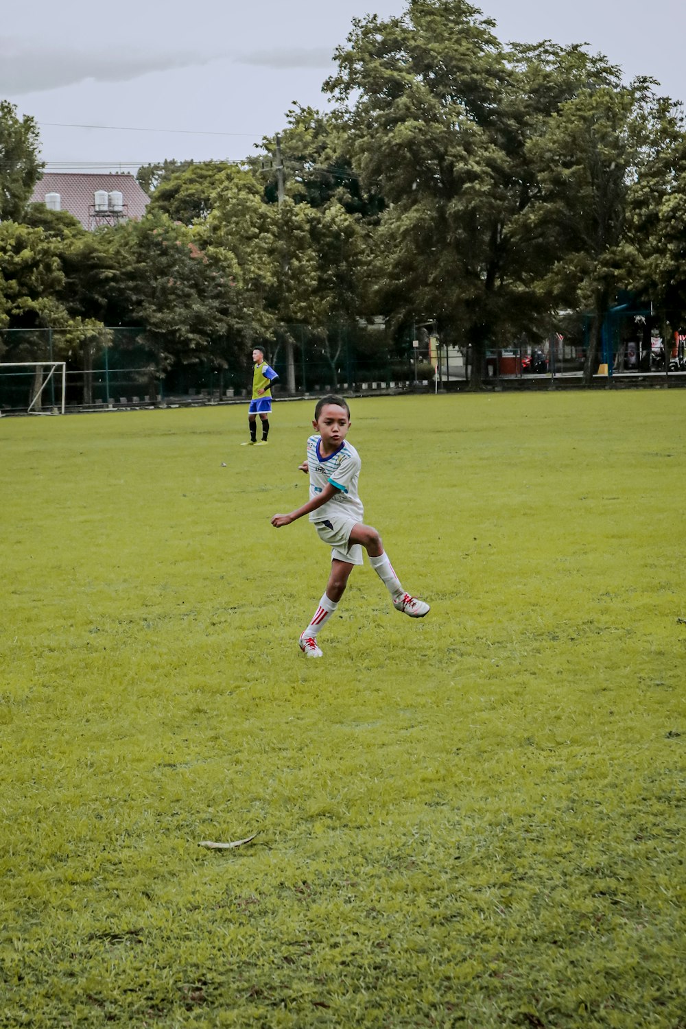 2 boys playing soccer on green grass field during daytime