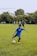 A young boy dribbling a soccer ball on a training field during practice.