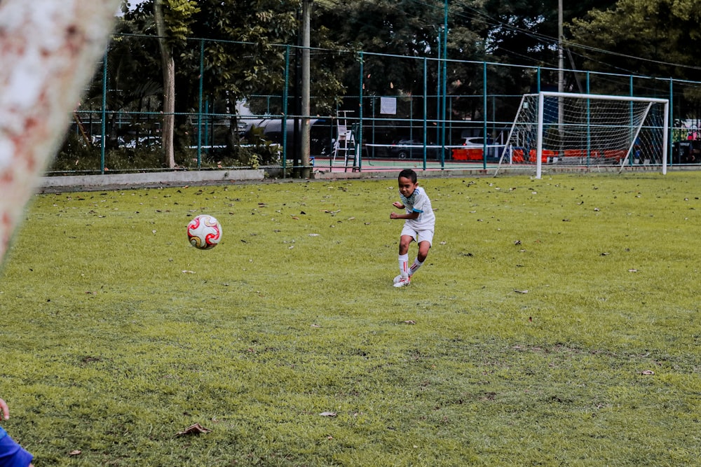 2 boys playing soccer on green grass field during daytime