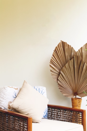 A cozy living room corner featuring woven rattan wall decor above a wooden side table with a ceramic vase set.