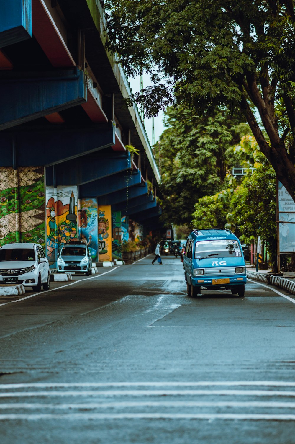 blue car parked beside green tree during daytime