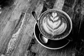 Barista creating latte art with a delicate rose gold spoon beside the cup.