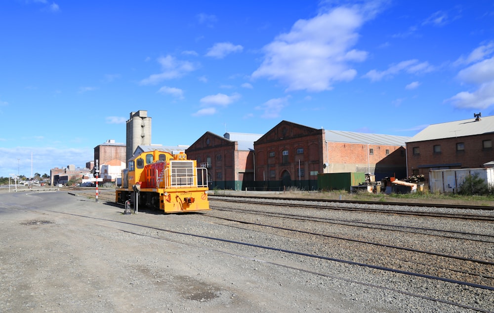 yellow and black train on rail road near brown building during daytime