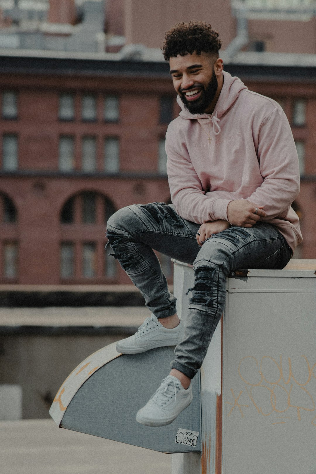 man in pink dress shirt and blue denim jeans sitting on white concrete bench during daytime