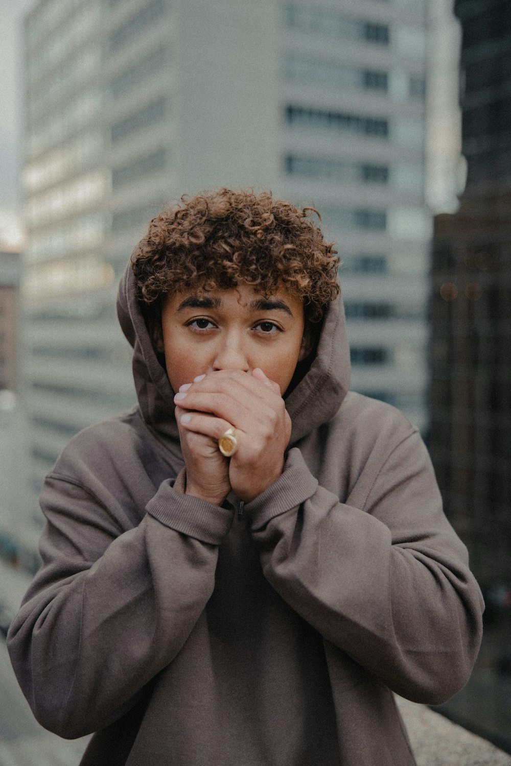 man in gray hoodie covering his mouth