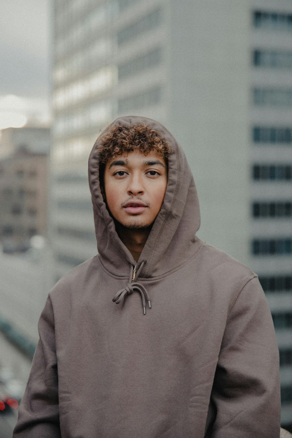 man in gray hoodie standing in front of white building during daytime