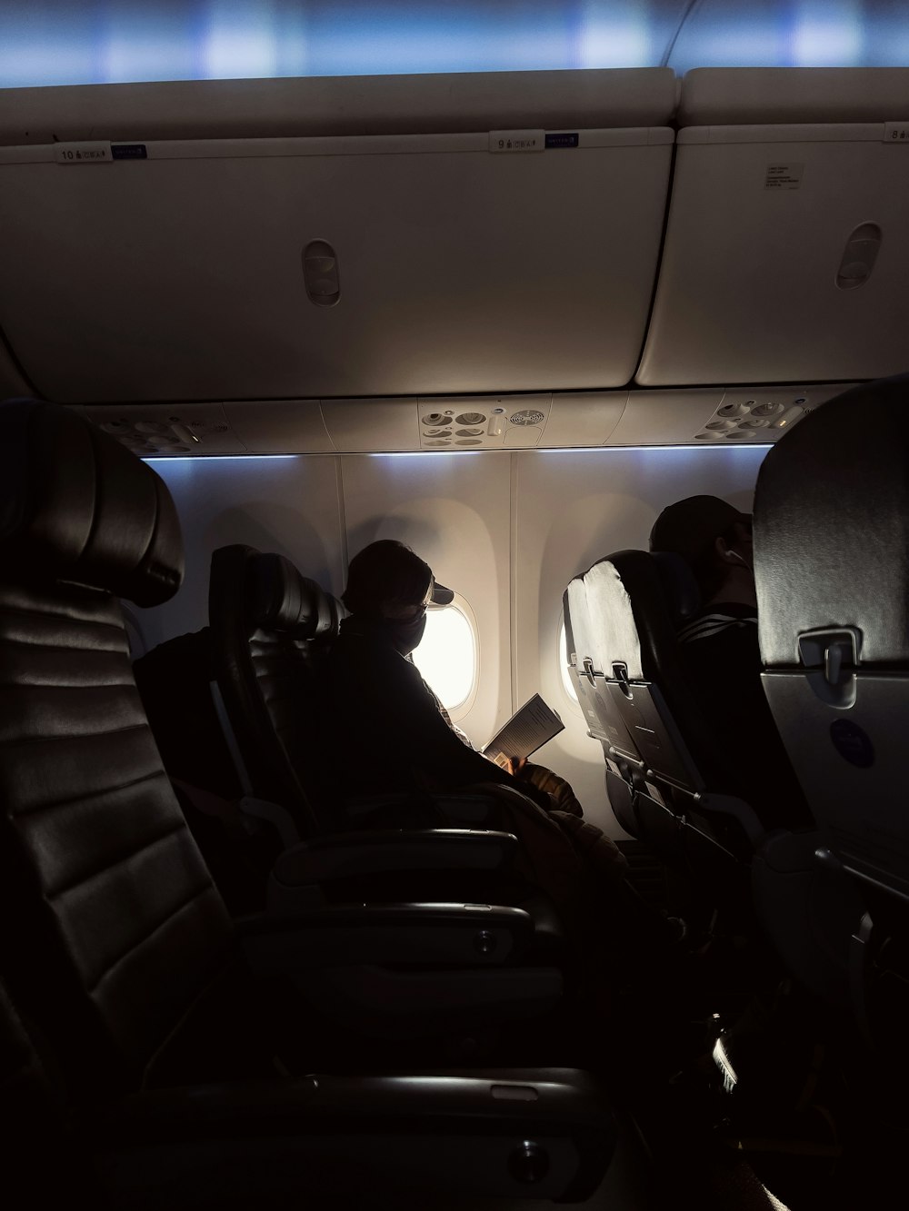 飛行機の座席に座る黒いジャケットの男