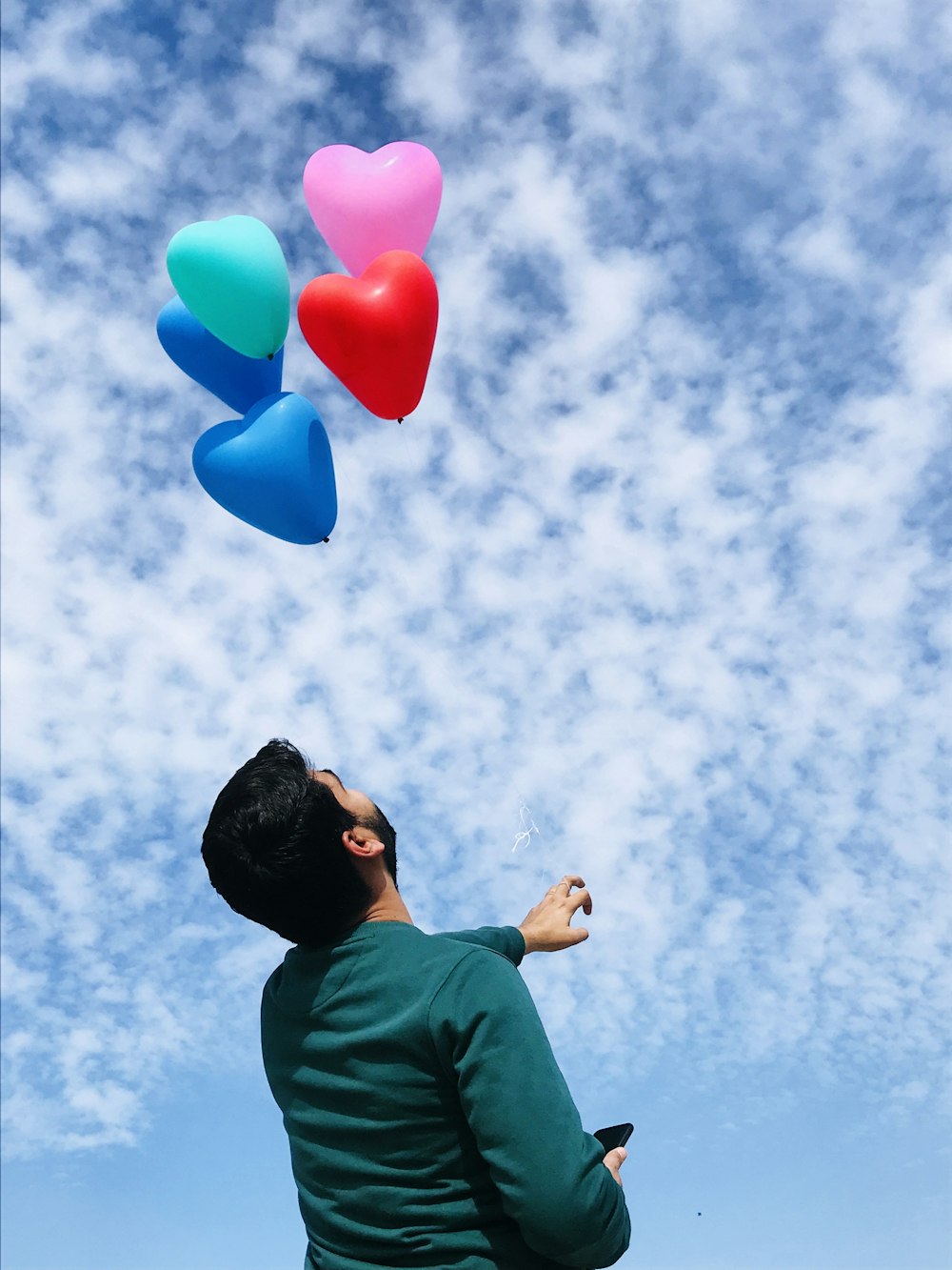 man in green shirt holding blue balloons