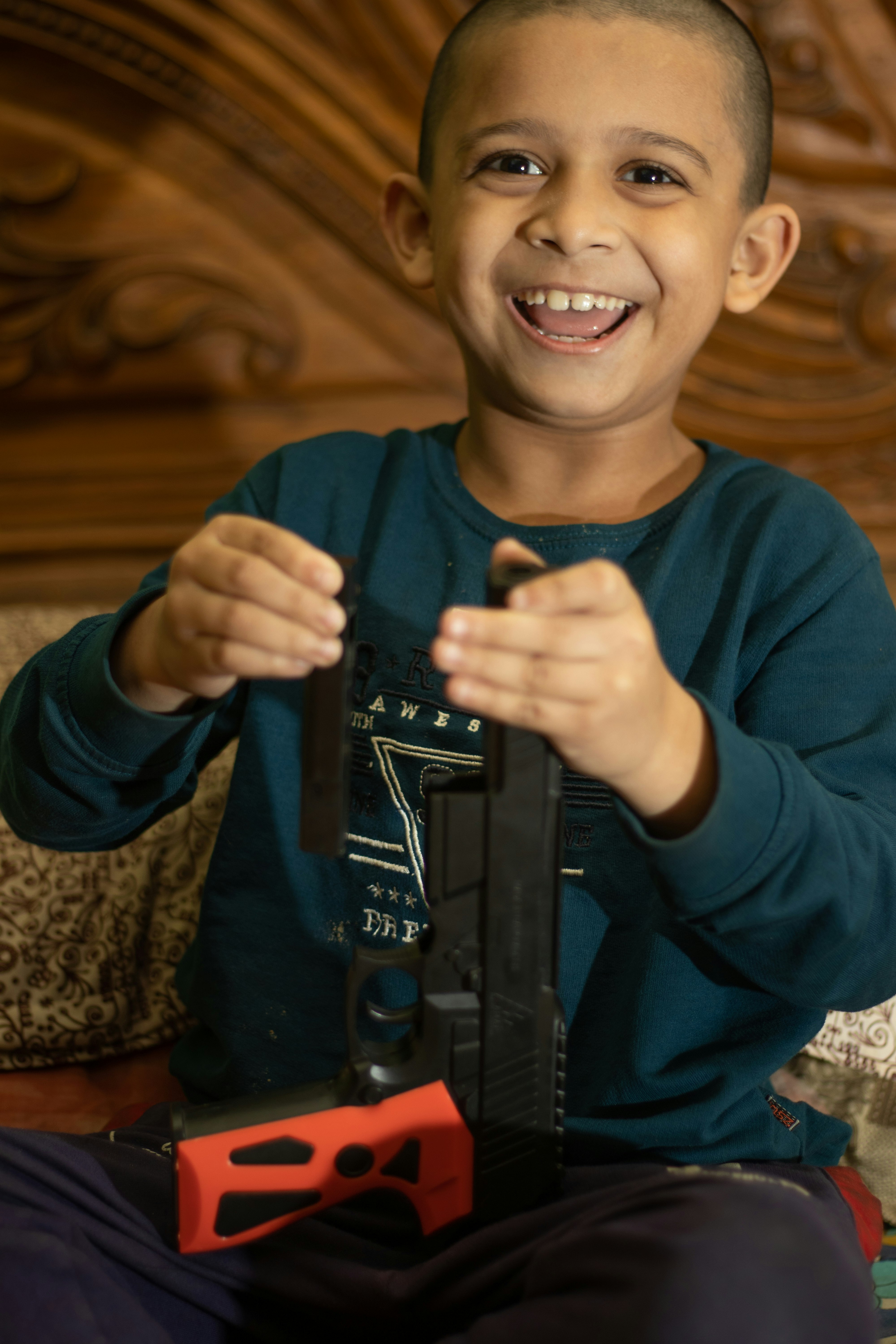 boy in blue sweater holding black rifle toy