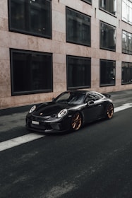 black porsche 911 parked near brown concrete building during daytime