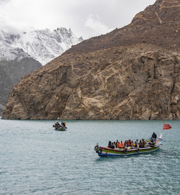 people riding on boat on sea near mountain during daytime