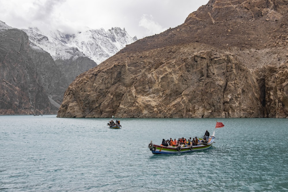 people riding on boat on sea near mountain during daytime