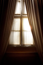 Close-up of elegant roman shades paired with sheer curtains filtering gentle daylight.