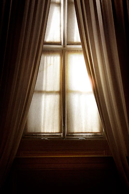 Elegant window curtains gently flowing in a breeze, showcasing delicate fabric texture.