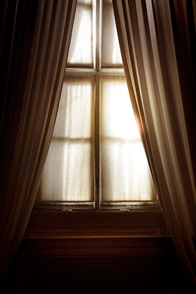 Elegant curtains gently flowing by a sunlit window