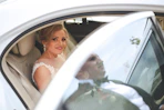 woman in white wedding dress sitting on car seat