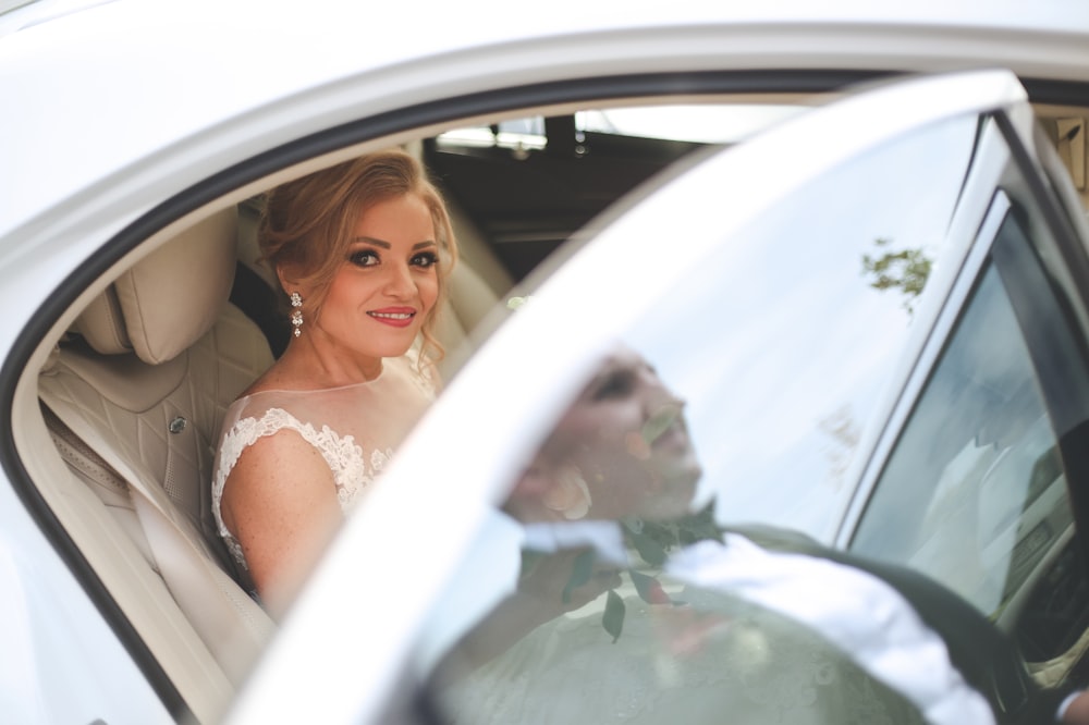 woman in white wedding dress sitting on car seat
