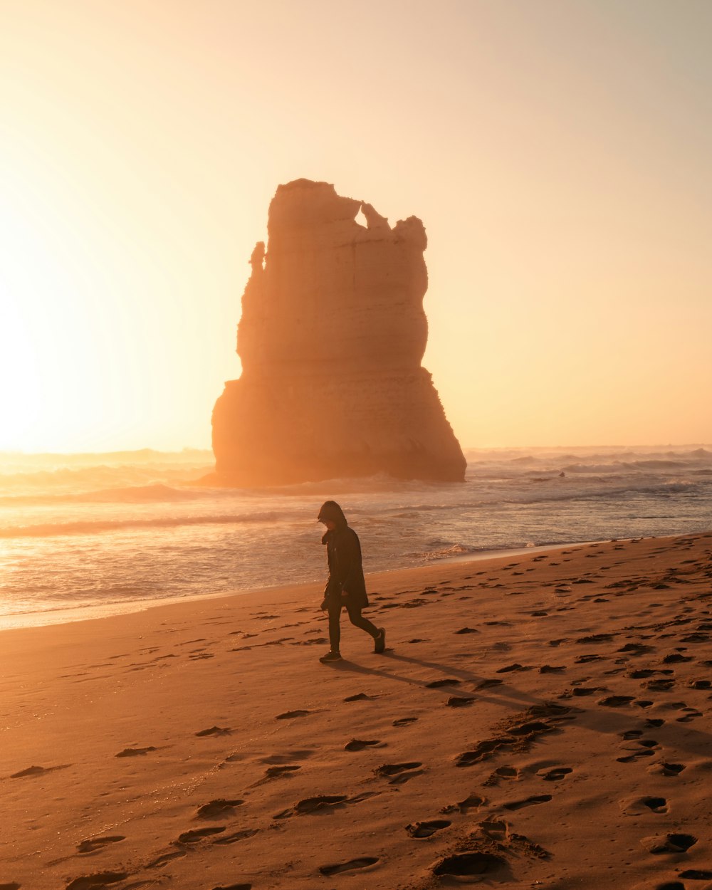 silhouette of woman walking on beach during sunset