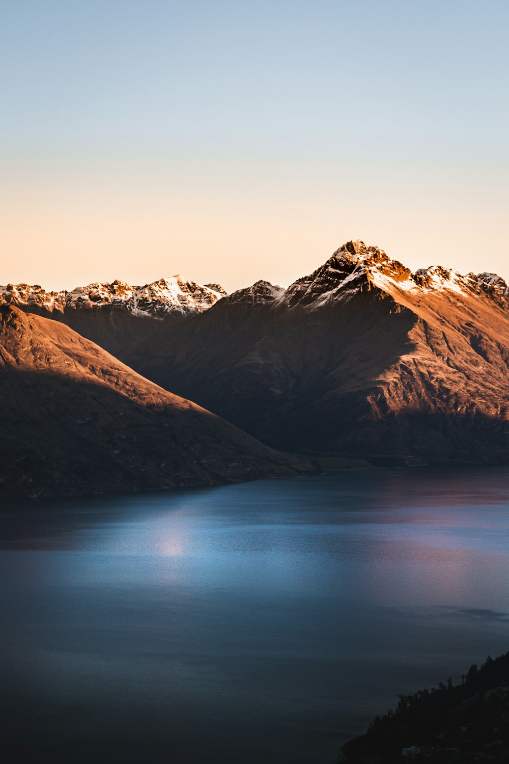 brown and white mountains beside body of water during daytime