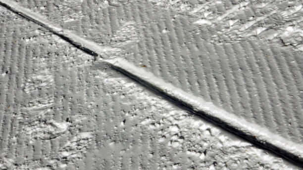 A snow-covered driveway cleared expertly with visible tire tracks and salted edges.