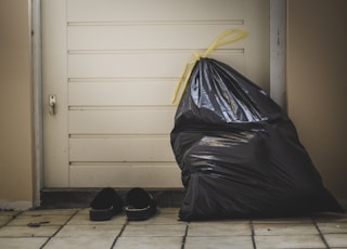 black plastic bag beside white wall