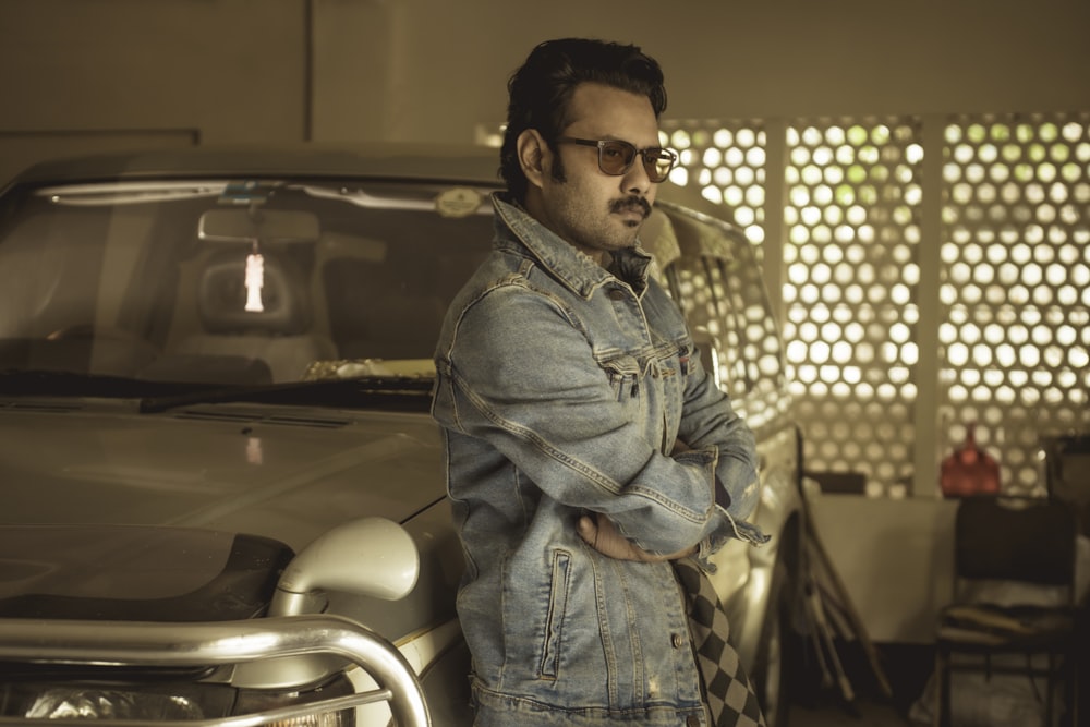 man in blue denim jacket and blue denim jeans standing near black car