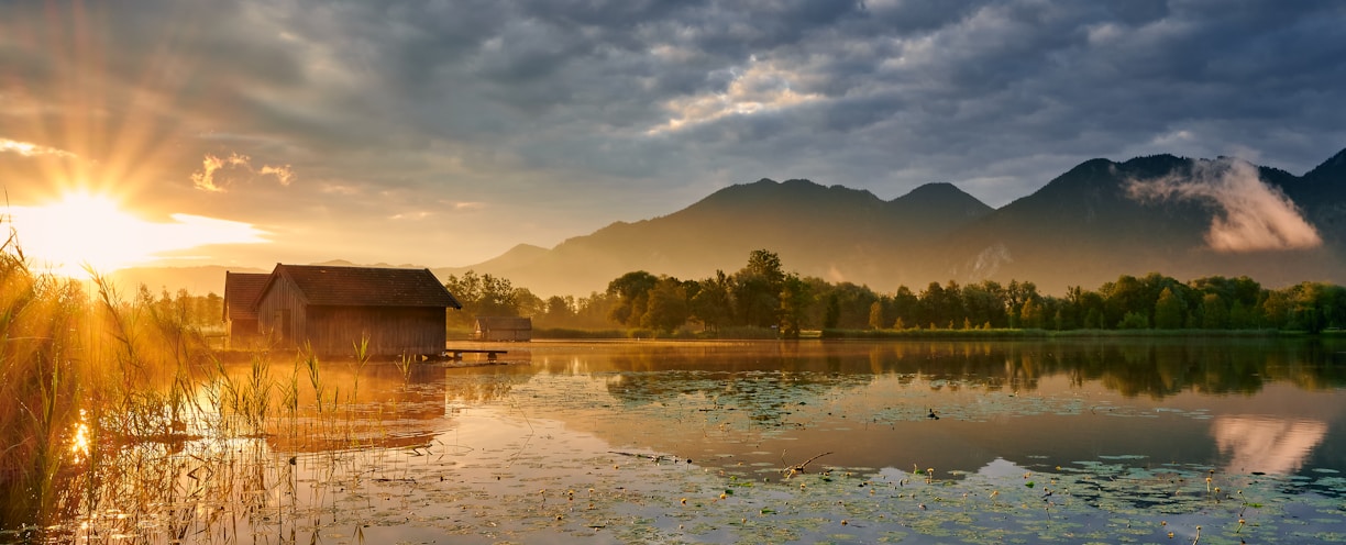 body of water near mountain under cloudy sky during daytime