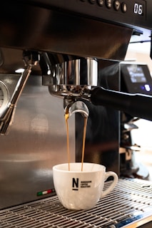 Close-up of a robotic arm pouring coffee into a cup.