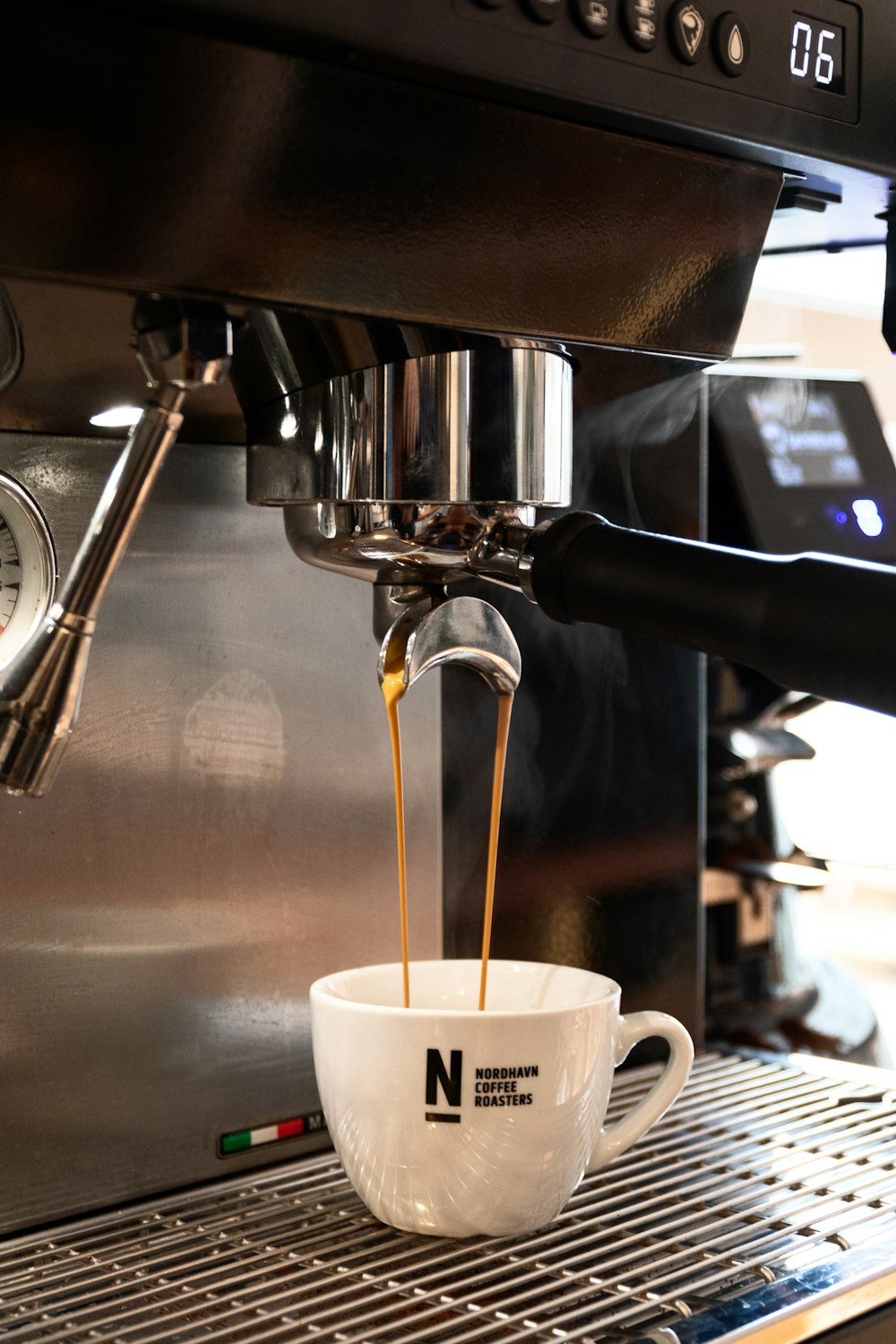 weiße Keramiktasse auf silberner Kaffeemaschine