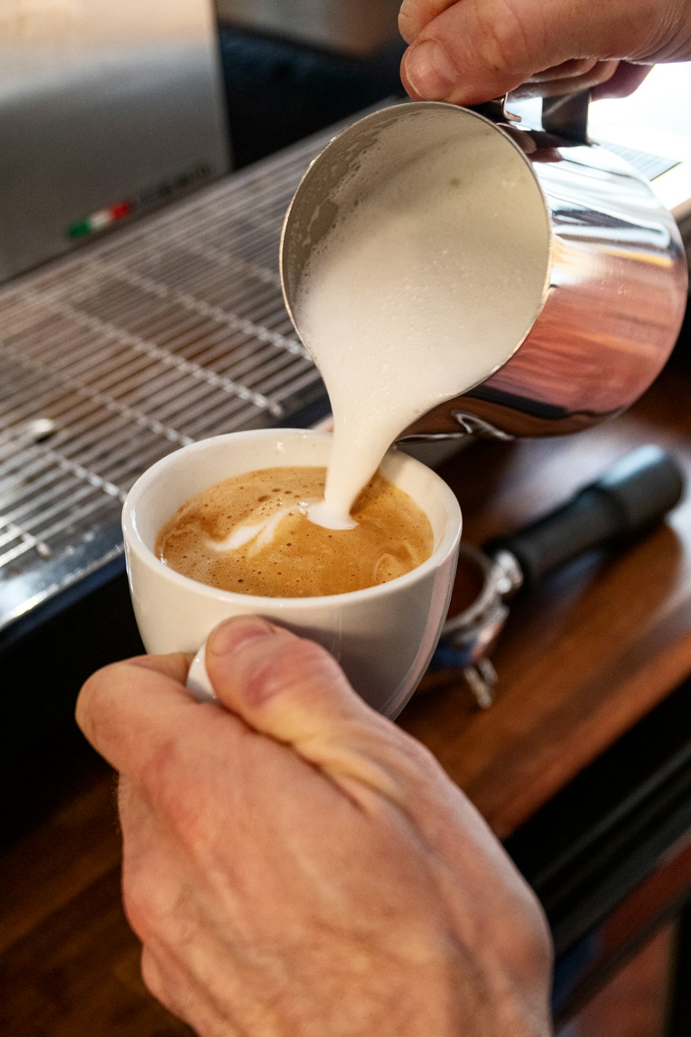 person holding white ceramic mug with brown liquid