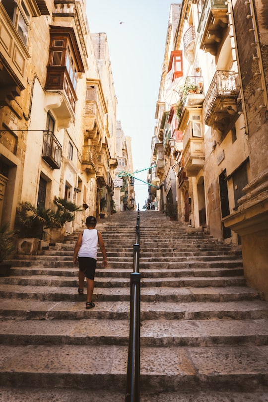 man in white t-shirt walking on gray concrete stairs during daytime in Valetta Malta