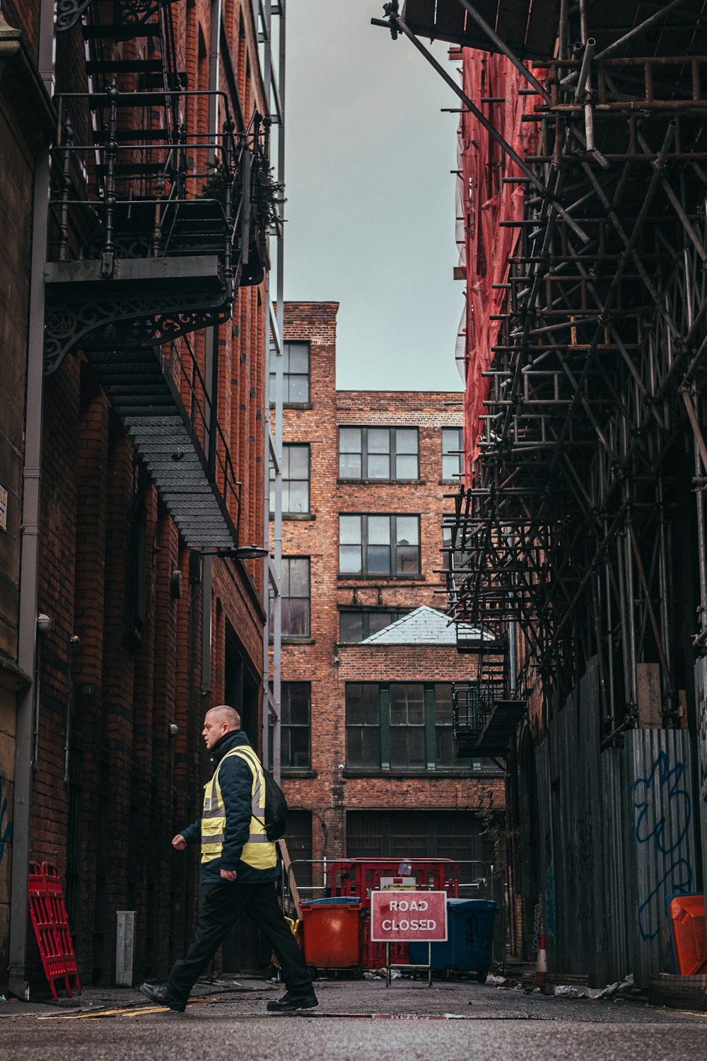 man in black jacket and yellow pants standing on black metal ladder during daytime