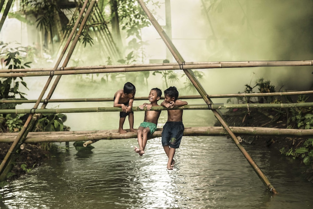 2 women in blue shorts sitting on brown wooden bridge during daytime