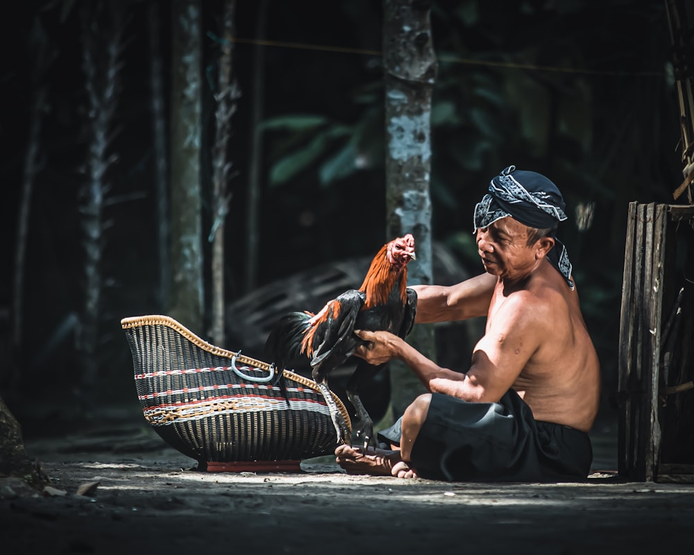 topless man sitting on floor near brown and white basket