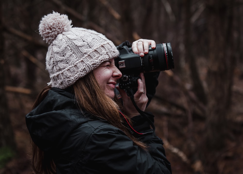 woman in black jacket using black dslr camera