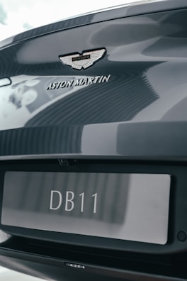 Silver Aston Martin DB11 shining on a winding country road.