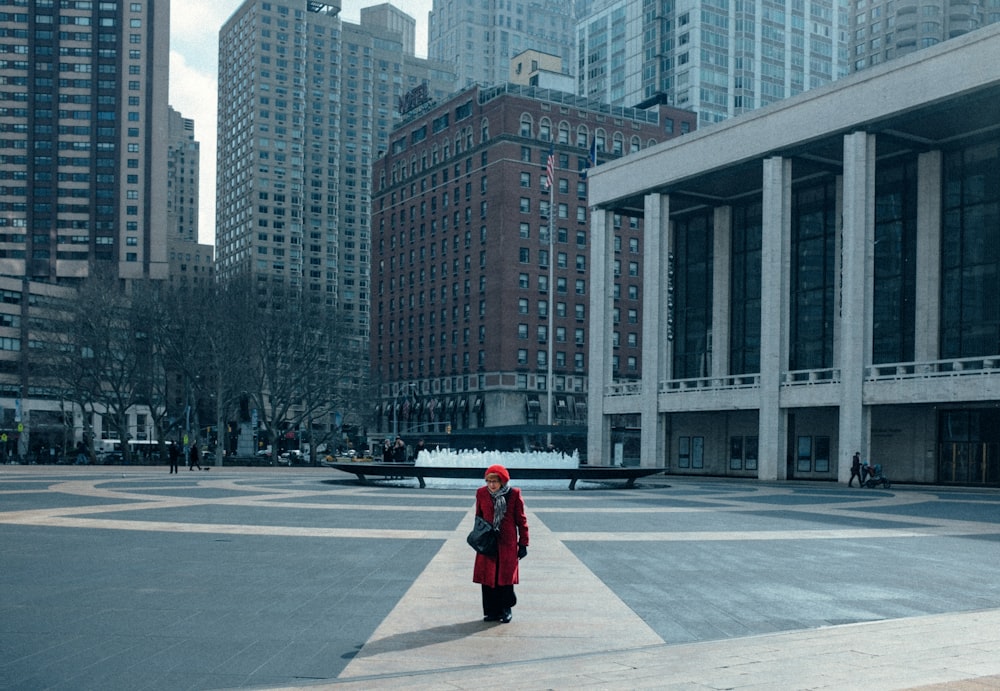 woman in red jacket walking on sidewalk during daytime