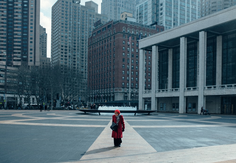 woman in red jacket walking on sidewalk during daytime