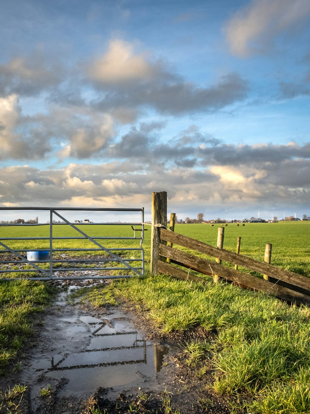 brown wooden fence on green grass field under cloudy sky during daytime