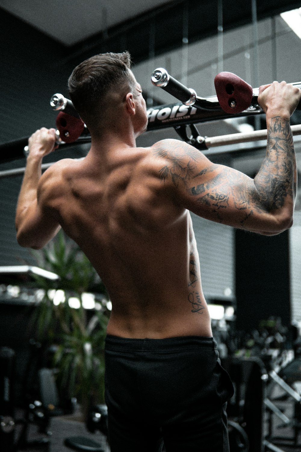 topless man in black shorts holding red and black kettle bell