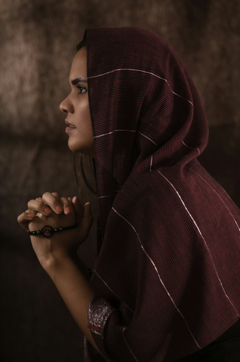 woman in red hoodie covering her face with her hands