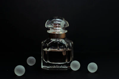 Close-up of the Essência Jotta perfume bottle with sleek design and urban graffiti backdrop.