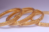 Bracelets and bangles stacked neatly on a minimalist white background.