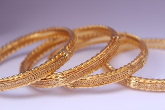 Bracelets and bangles stacked neatly on a minimalist white background.