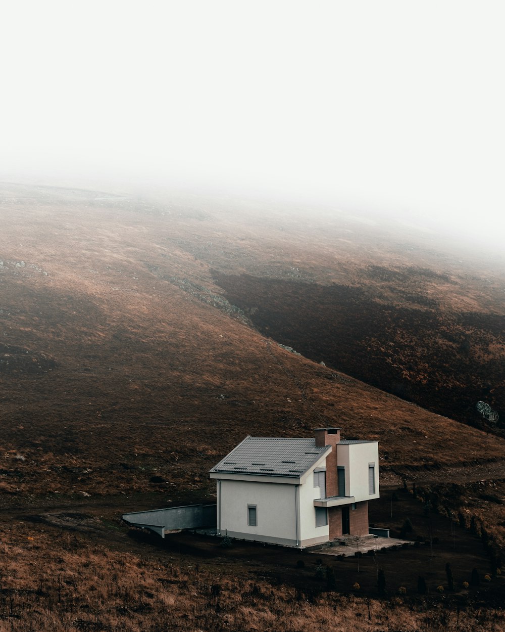 white and gray house on brown field near brown mountains during daytime