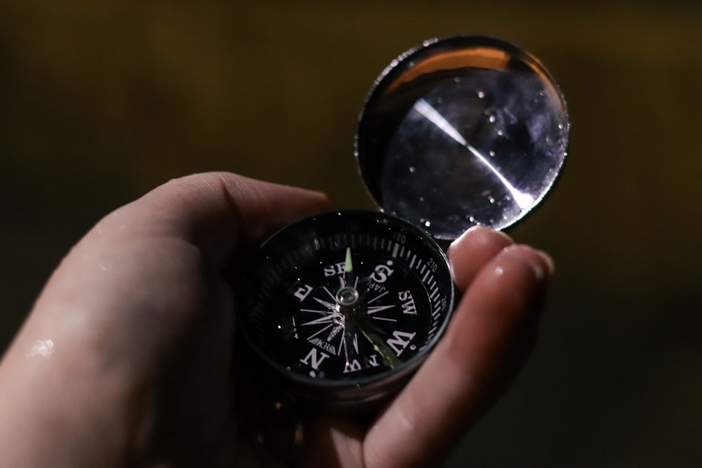 person holding silver and black compass